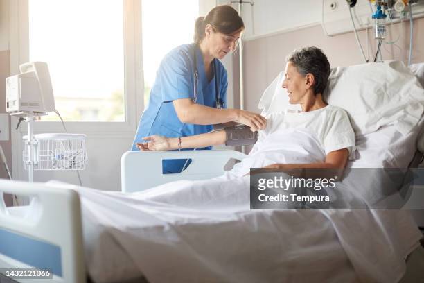 enfermera ajustando el monitor de presión arterial en paciente hospitalaria - hospital patient fotografías e imágenes de stock