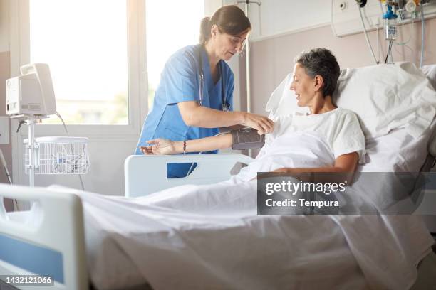 female nurse adjusting the blood pressure monitor on female hospital patient - ward bildbanksfoton och bilder