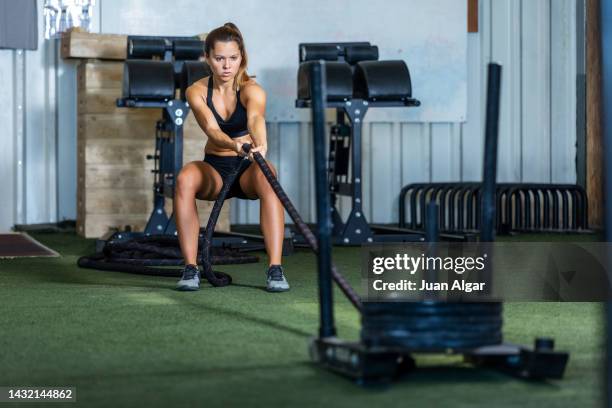 young sportswoman pulling rope with weight - pulling sledge stock pictures, royalty-free photos & images