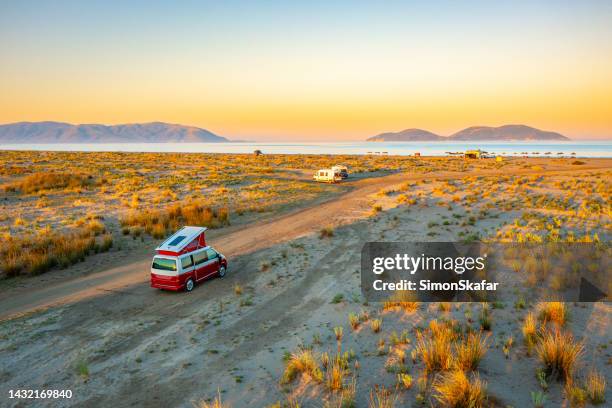campervans moving amidst sandy beach against sky during sunset - albania stock pictures, royalty-free photos & images