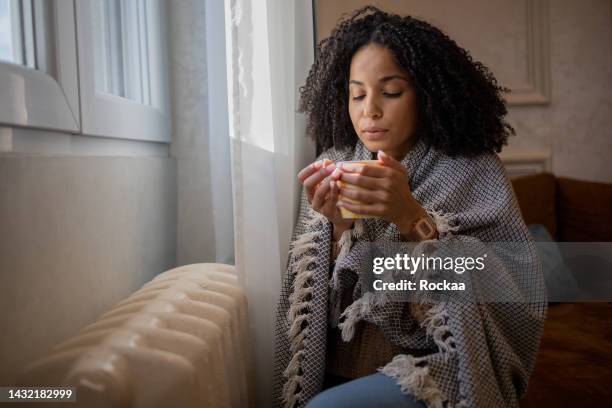 woman feel cold in home with no heating - wrapped in a blanket stock pictures, royalty-free photos & images