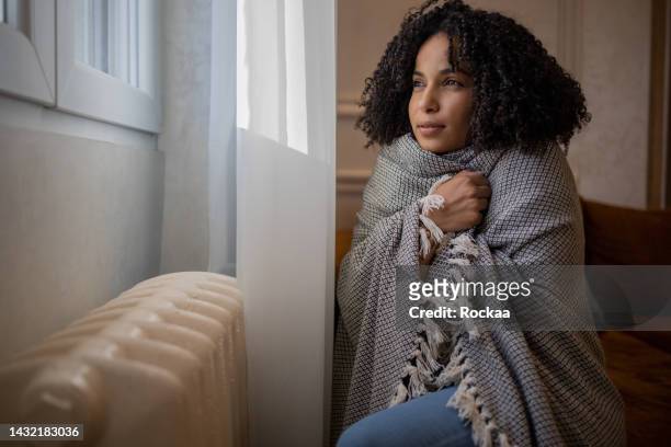 woman feel cold in home with no heating - wrapped in a blanket stock pictures, royalty-free photos & images