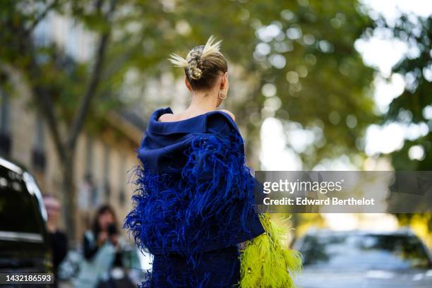 Leonie Hanne wears a black shoulder-off top, a navy blue with royal blue embroidered feathers / felt wool jacket from Elie Saab, a matching royal...