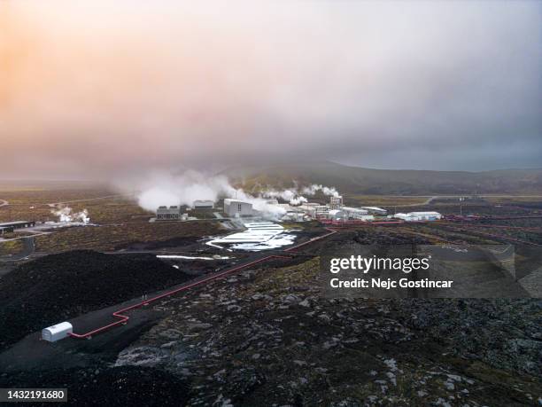 aerial view of steaming geothermal power plant producing energy - geothermische centrale stockfoto's en -beelden