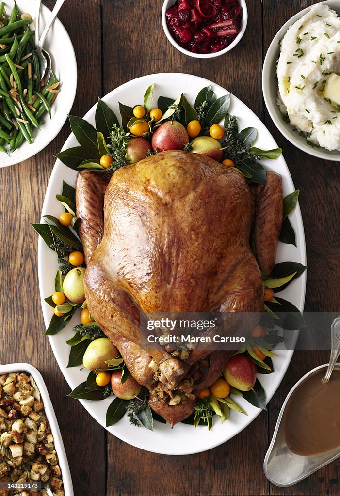 Turkey, stuffing, and gravy dishes on wood surface