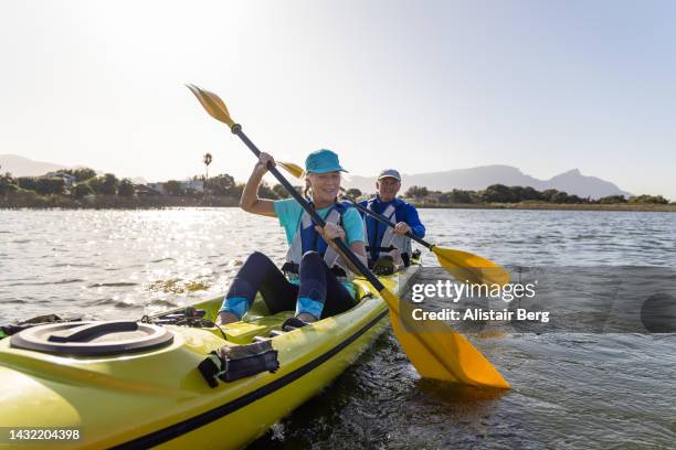 senior couple kayaking on a lake together at sunset - piragüismo fotografías e imágenes de stock