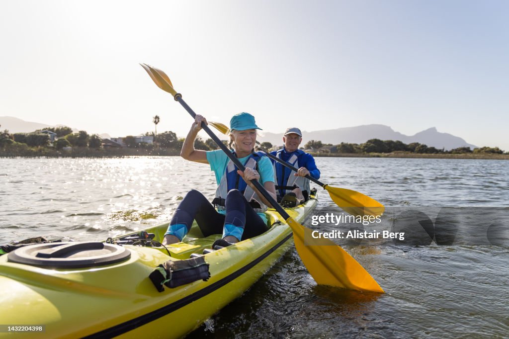 Senior couple kayaking on a lake together at sunset