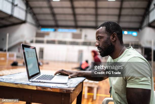 soldier using the laptop at a community center - natural disaster volunteer stock pictures, royalty-free photos & images