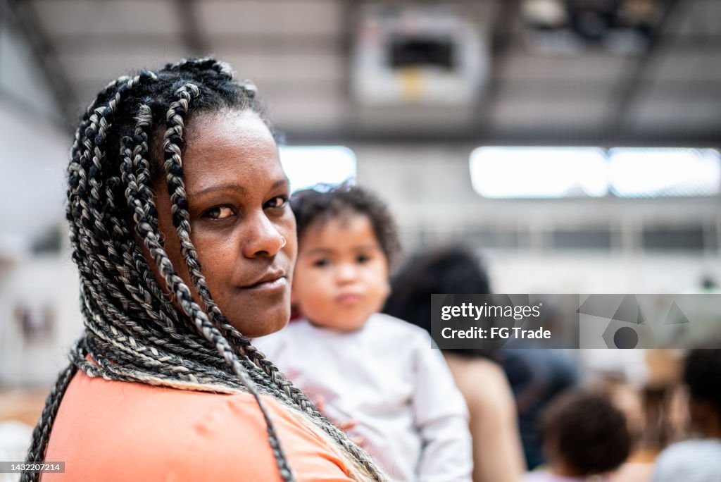 Portrait of a mature woman carrying her son waiting in line at a community center