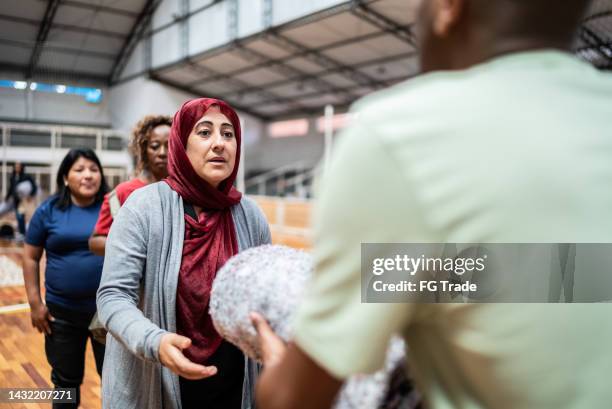 mature middle eastern woman receiving a blanket from a soldier at a community center - middle east crisis stock pictures, royalty-free photos & images