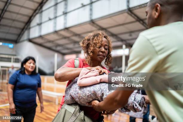 ältere frau erhält eine decke von einem soldaten in einem gemeindezentrum - emergency shelter stock-fotos und bilder