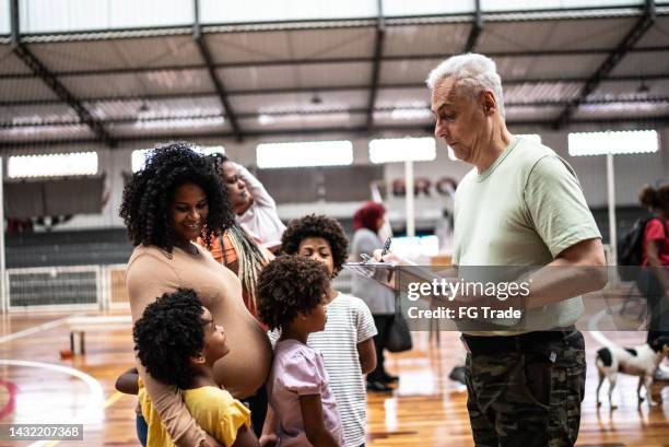 soldier registering a pregnant young woman with children at a community center - 1 year poor african boy stock pictures, royalty-free photos & images