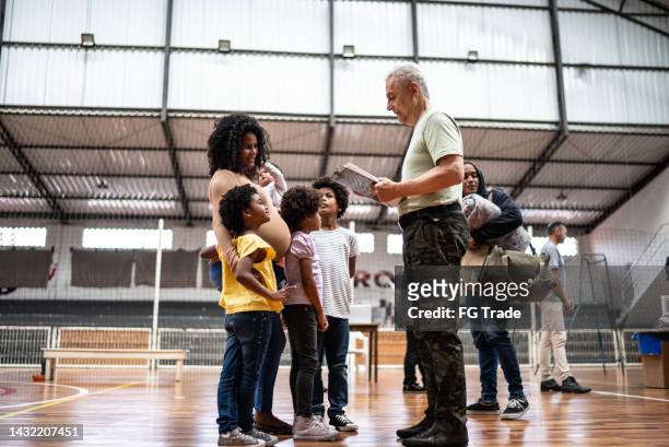 soldier registering a pregnant young woman with children at a community center - 1 year poor african boy stock pictures, royalty-free photos & images