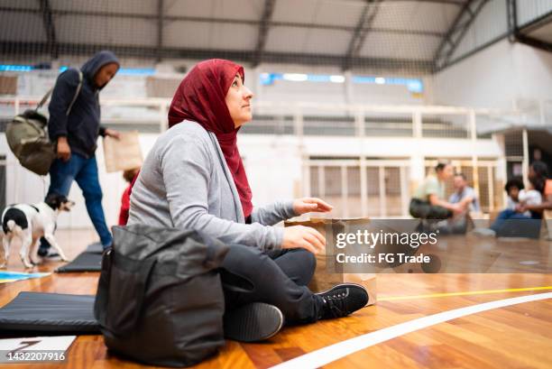 mujer refugiada con hijab rezando en un refugio - sitting on floor fotografías e imágenes de stock