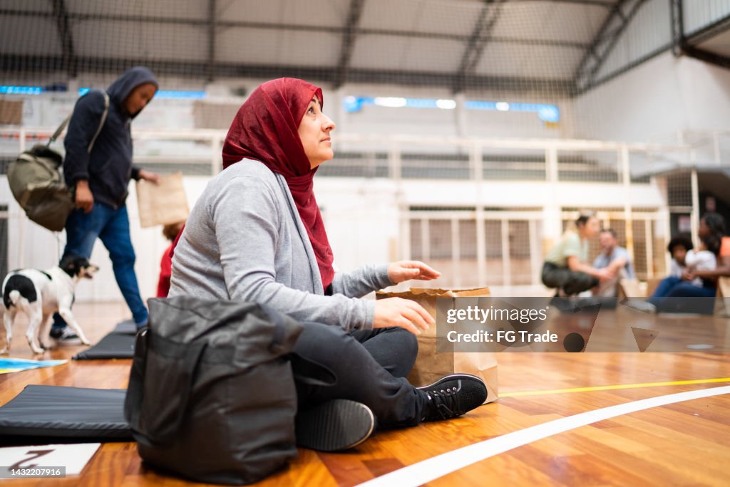 Refugee woman wearing hijab praying in a sheltering