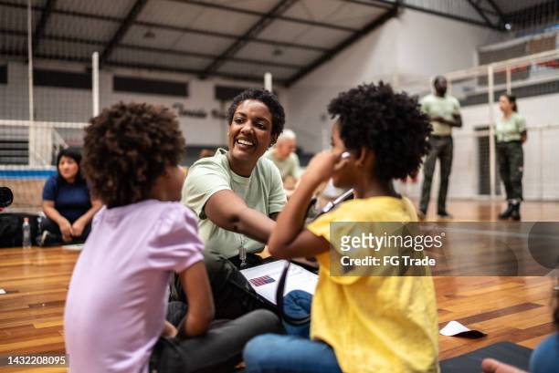 médico del ejército jugando con niños refugiados en un centro comunitario - children charity fotografías e imágenes de stock