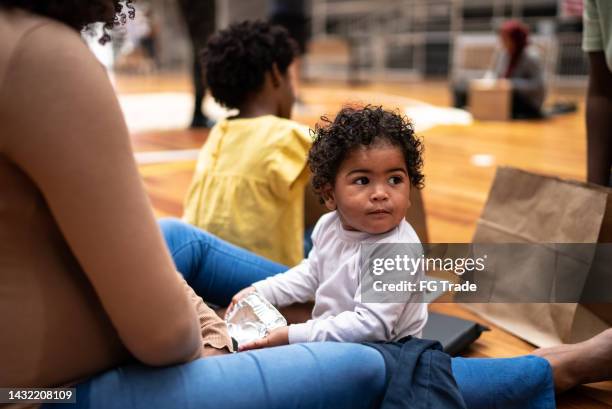 kleiner junge mit mutter in einer flüchtlingsunterkunft - notunterkunft stock-fotos und bilder