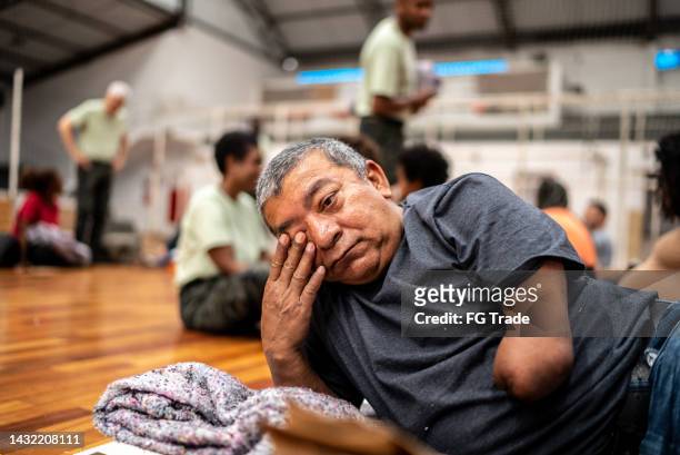 disabled man lying down in a sheltering at a community center - homeless shelter man stock pictures, royalty-free photos & images