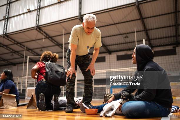 soldier talking to a refugee man with a dog at a community center - red cross stock pictures, royalty-free photos & images