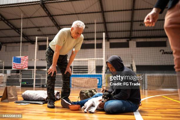 soldier talking to a refugee man with a dog at a community center - drug addiction stock pictures, royalty-free photos & images