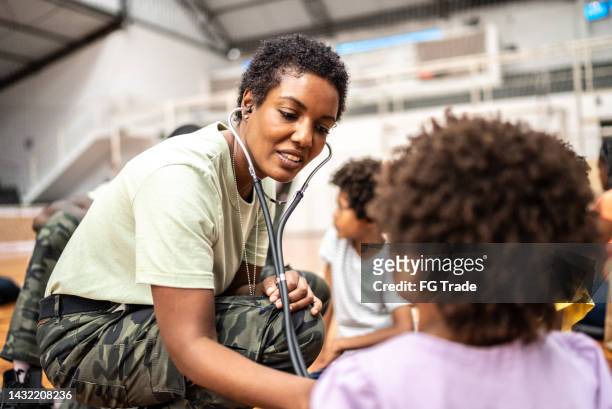 army doctor examining refugee children at a community center - armed forces people stock pictures, royalty-free photos & images