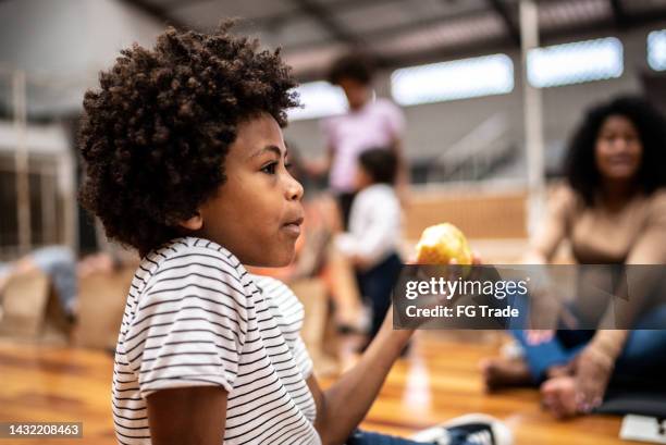 boy eating an apple at a community center - homeless person eating stock pictures, royalty-free photos & images