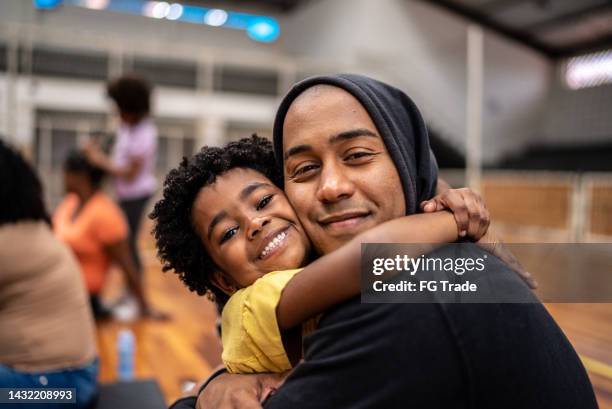 porträt von vater und tochter, die sich in einem gemeindezentrum umarmen - zuflucht stock-fotos und bilder