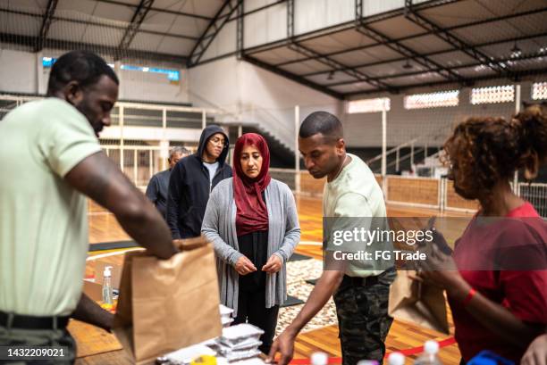 soldiers giving food to people at a community center - african refugee stock pictures, royalty-free photos & images