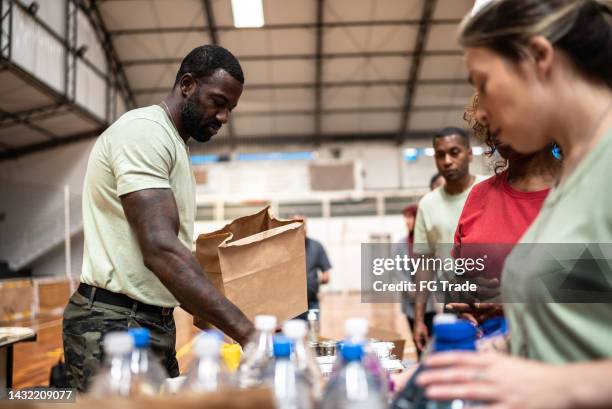 soldiers giving food to people at a community center - distribution center stockfoto's en -beelden