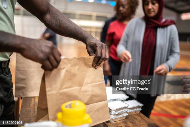soldier giving food to people at a community center - food insecurity stock pictures, royalty-free photos & images