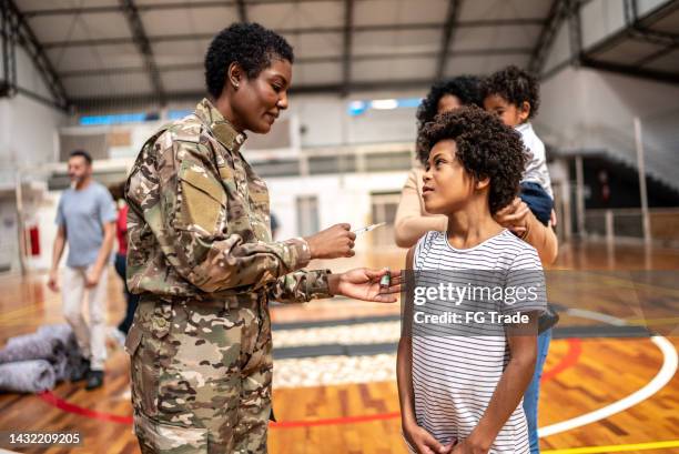 soldier vaccinating a boy at a community center - nurse conflict stock pictures, royalty-free photos & images