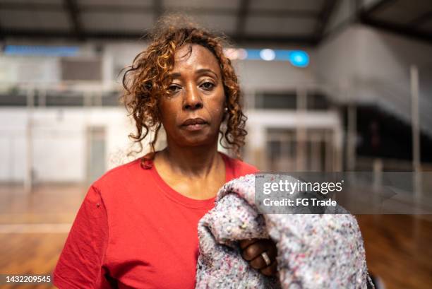 portrait of a senior woman holding a blanket at a community center - homelessness stockfoto's en -beelden