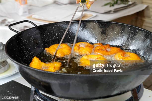woman frying ball cakes on frying pan - frituur stockfoto's en -beelden