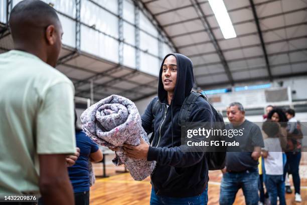joven recibiendo una manta de un soldado en un gimnasio - refugiados fotografías e imágenes de stock