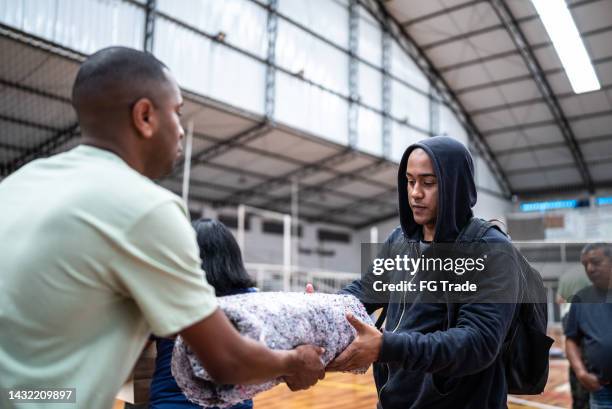 young man receiving a blanket from a soldier at a gymnasium - the missionaries of charity stock pictures, royalty-free photos & images