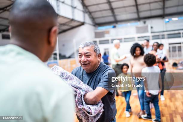 disabled mature man receiving a blanket from a soldier at a gymnasium - organisation for migration stock pictures, royalty-free photos & images