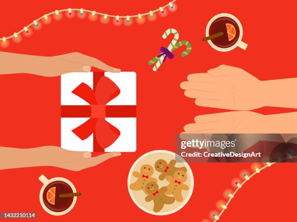 hands giving gift and celebrating christmas. top view of table with mulled wine, gingerbread cookies and candy canes - christmas table stock illustrations