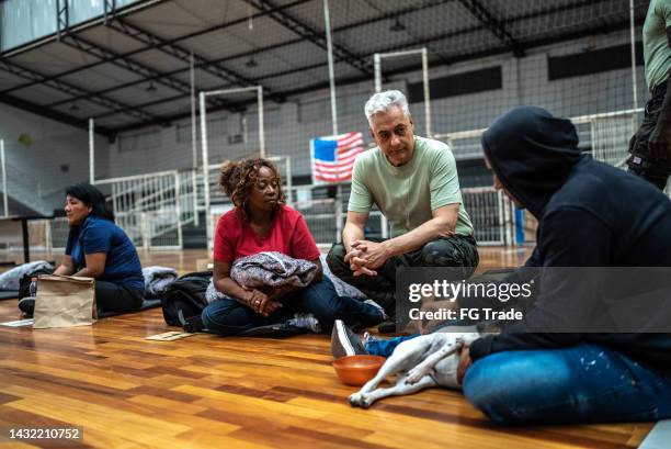 soldier talking to refugees in a sheltering - illegale immigrant stockfoto's en -beelden