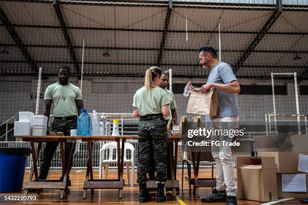 soldiers giving donations to refugees in a sheltering - homeland security stock pictures, royalty-free photos & images