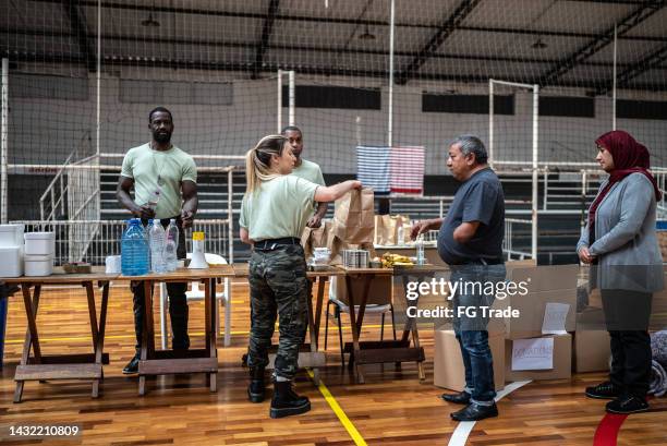 soldiers giving donations to refugees in a sheltering - homeland security stock pictures, royalty-free photos & images