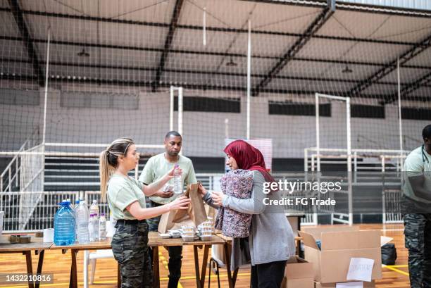 soldiers giving donations to refugees in a sheltering - helping refugee stock pictures, royalty-free photos & images