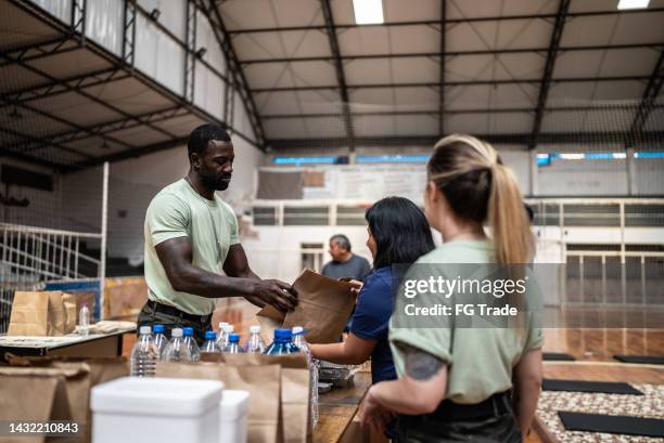 soldiers giving donations to refugees in a sheltering - natural disaster volunteer stock pictures, royalty-free photos & images