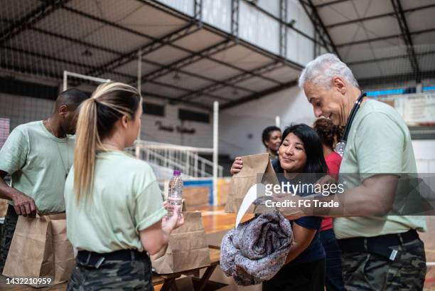 soldier with a clipboard giving donations to refugees in a sheltering - homeland security stock pictures, royalty-free photos & images