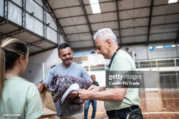 soldado com uma prancheta dando doações a refugiados em um abrigo - homeless person - fotografias e filmes do acervo