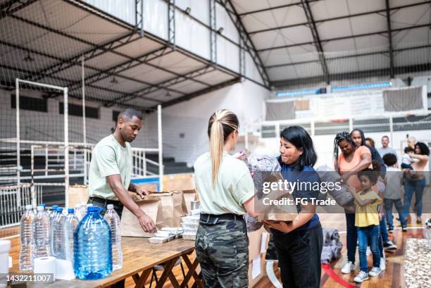 soldiers giving donations to refugees in a sheltering - refugee aid stock pictures, royalty-free photos & images