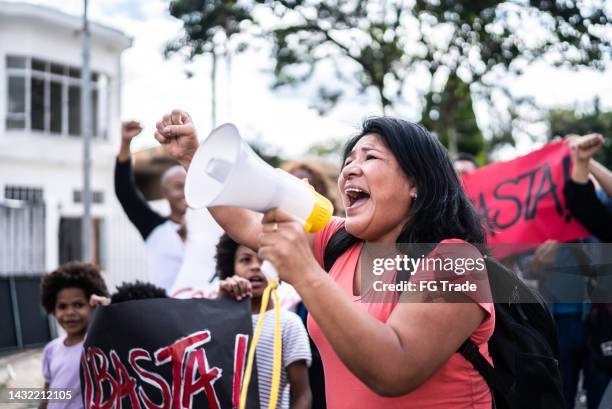 mature woman talking in a megaphone during a protest in the street - activists protests outside of trump tower in chicago stockfoto's en -beelden