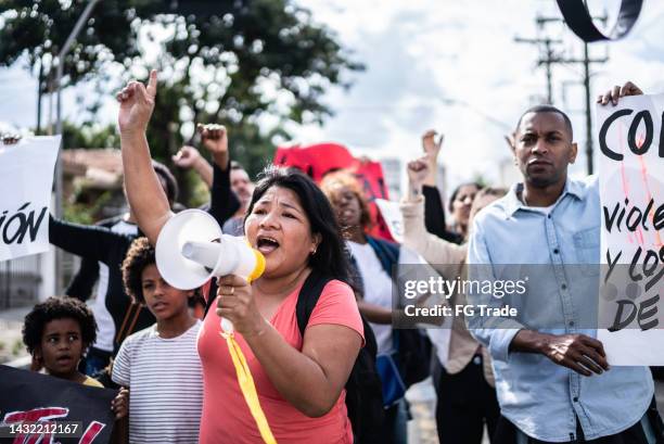 mature woman talking in a megaphone during a protest in the street - human rights protest stock pictures, royalty-free photos & images