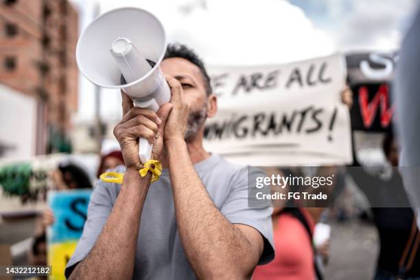 mature man talking in a megaphone during a protest in the street - refugee protest stock pictures, royalty-free photos & images