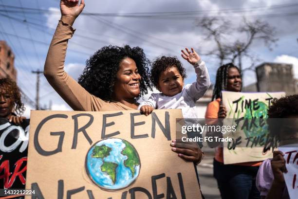 junge frau mit ihrem sohn protestiert auf der straße - environmental protest stock-fotos und bilder