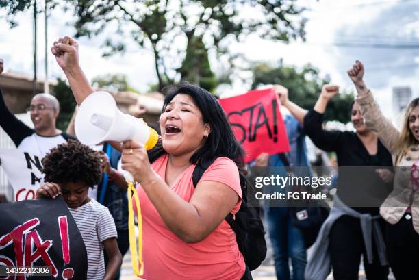 reife frau spricht in einem megaphon während eines protests auf der straße - childrens justice campaign event stock-fotos und bilder